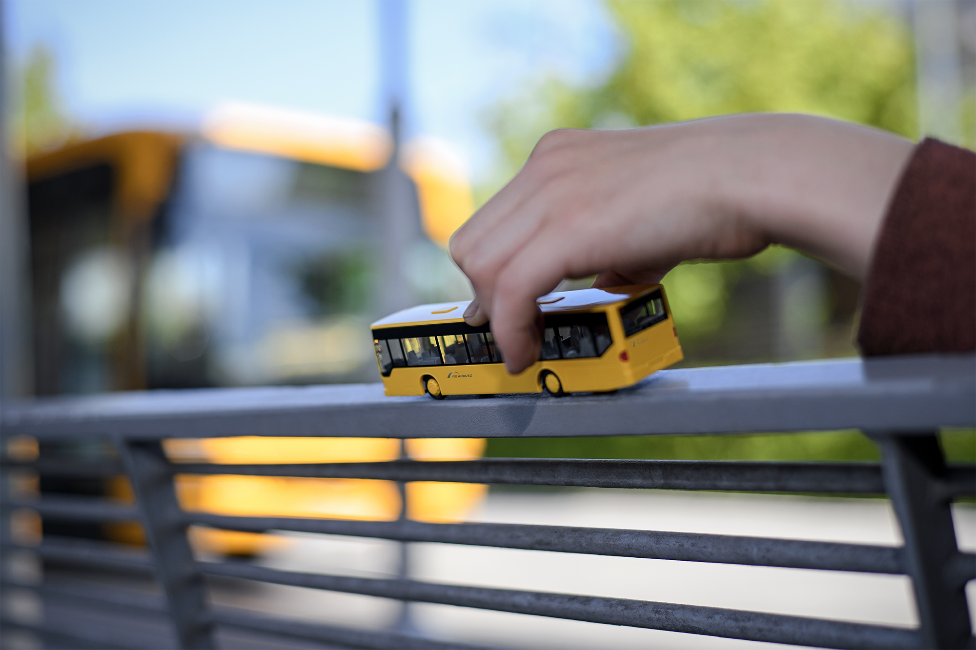 A képen egy gyermek kezében lévő játék autóbusz látható.